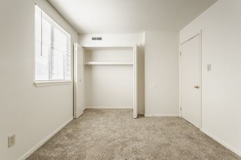 An empty bedroom with a closet and a window